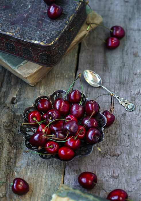 Freshly harvested black cherries and vintage apothecary objects inspiring the Black Cherry Scented Candle