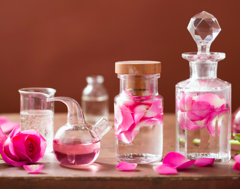 Vintage perfume bottles and rose petals inspiring the Old Rose Scented Candle